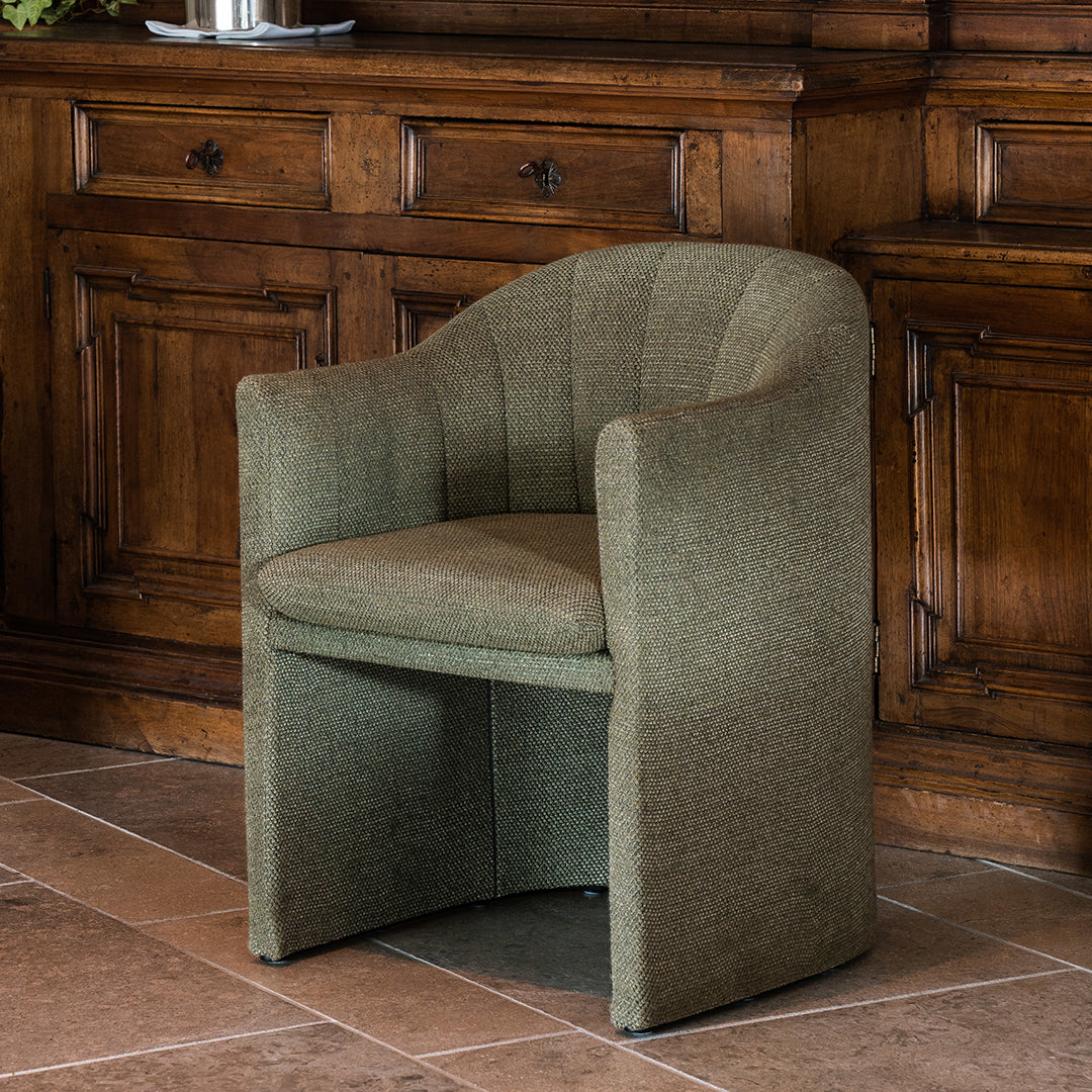 Olive green upholstered armchair with a ribbed texture, featuring a smooth and modern curved design.
