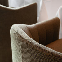 Textured brown upholstery with subtle ribbed pattern on a modern curved armchair. Elegant and cozy design.