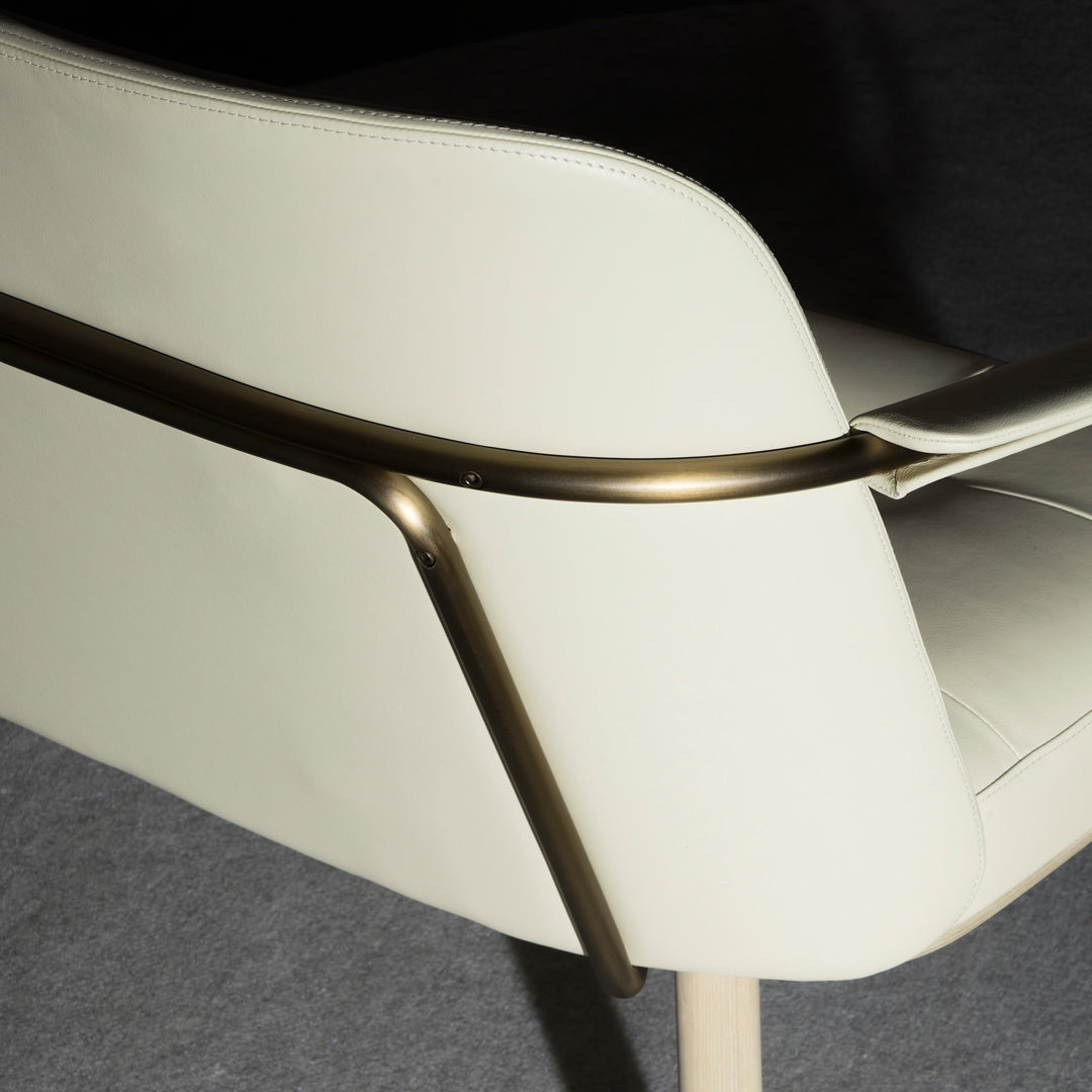 Cream leather chair with sleek metallic accents and clean lines, set against a dark gray background.