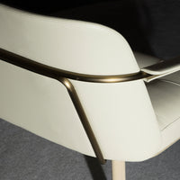 Cream leather chair with sleek metallic accents and clean lines, set against a dark gray background.