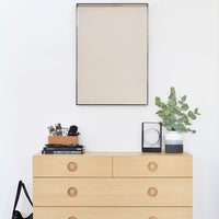 Natural wood dresser with light tones and round, wooden knobs. Minimalist decor in neutral colors, adding a modern touch.