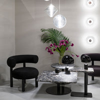 Black chairs, marble tables, and vibrant purple flowers against a neutral backdrop highlight modern design trends.