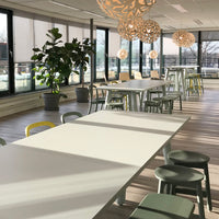 Bright white tables, light green chairs, and soft yellow accents in a modern, airy workspace.