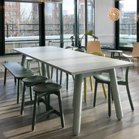 Modern dining table featuring a white top, light gray legs, and green and yellow accent chairs.
