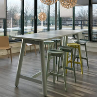 Modern bar table in light gray with pastel green and yellow stools, featuring a sleek minimalist design and natural wood accents.