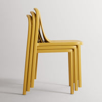 Stack of four modern chairs in vibrant mustard yellow, showcasing sleek curves and minimalistic design.