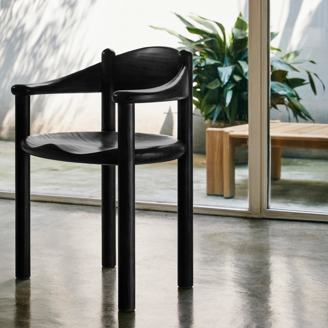 Black wooden chair with smooth curves and a minimalist design, set against a bright, airy background.