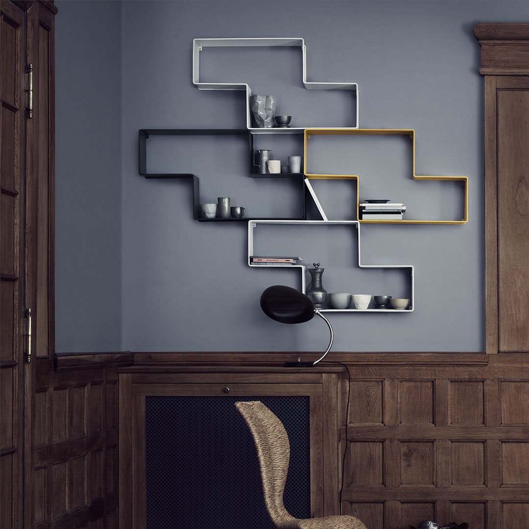 Modern wall shelf design with geometric patterns in gray, black, and gold accents against a deep blue wall.