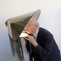 Sleek black and silver lamp with a modern conical shape, reflecting light and creating unique patterns.