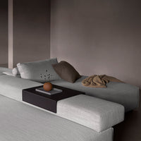 Gray sectional sofa with textured cushions in soft beige and dark brown accents, featuring a sleek black side table.