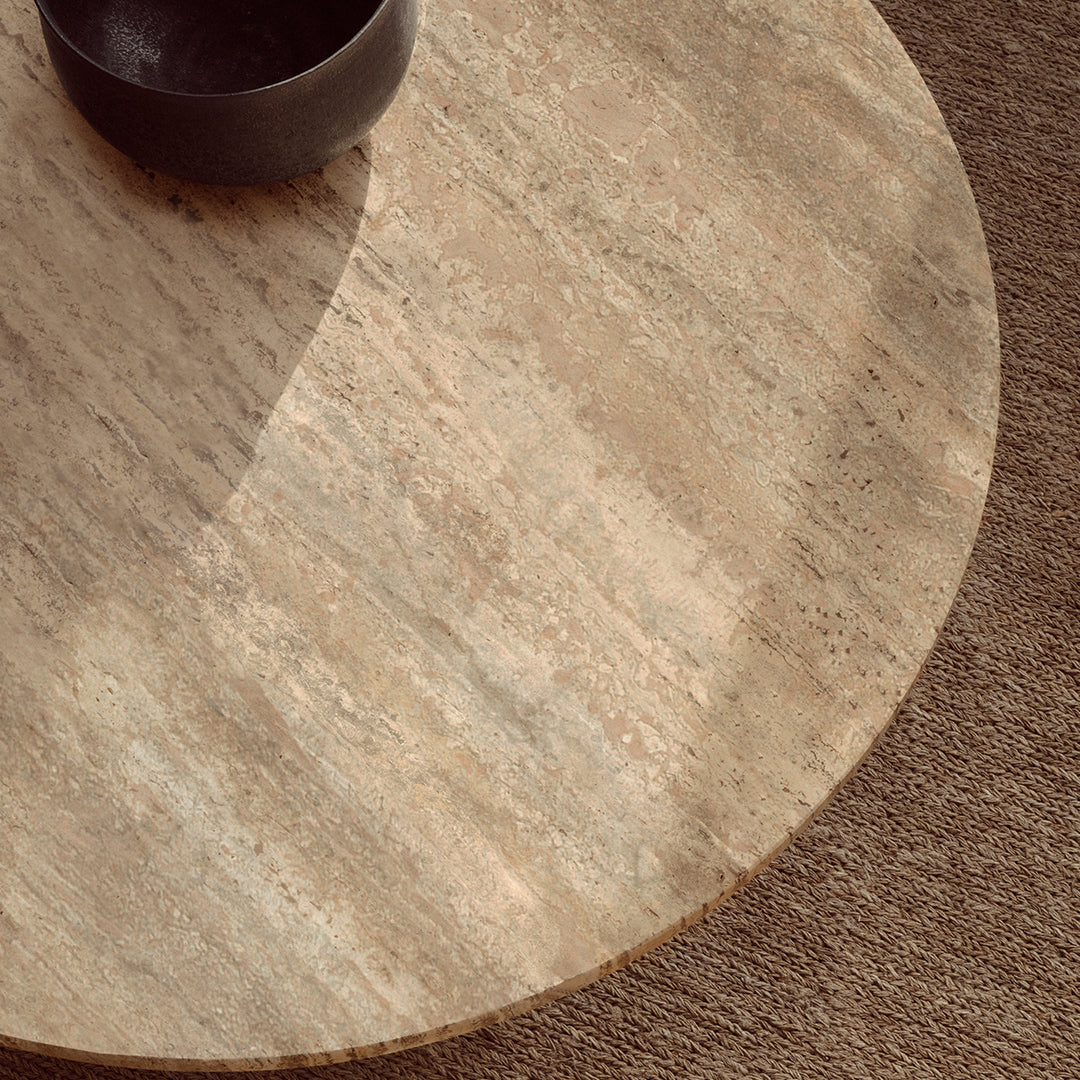 Round stone table featuring a soft beige hue with subtle texture patterns, complemented by a dark bowl.