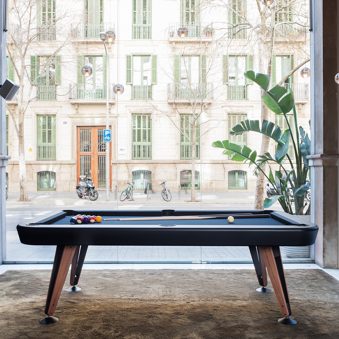 Stylish black pool table with rich wooden legs, featuring vibrant colored balls and soft beige carpet.