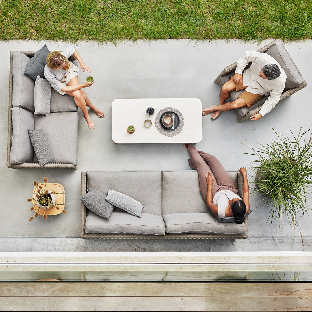 Stylish gray outdoor furniture set with minimalist design and neutral cushions on a textured concrete patio.