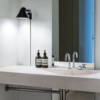 Modern bathroom with beige countertop, black lamp, mirrored surfaces, and sleek chrome fixtures.