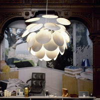 Elegant white pendant lamp with petal-like layers, casting soft light against a chic, modern backdrop.
