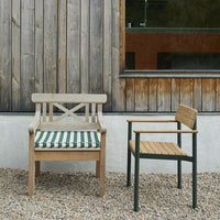 Wooden chairs in natural tones with a green and white striped cushion, set against a rustic wooden backdrop.