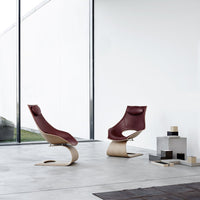 Modern rocking chairs with burgundy leather upholstery and curved wooden bases, showcased in a minimalist setting.