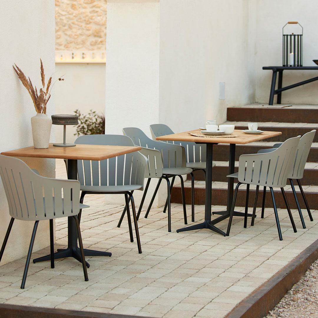 "Modern outdoor dining set featuring gray chairs and a wooden table, set on a neutral stone patio."