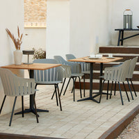 "Modern outdoor dining set featuring gray chairs and a wooden table, set on a neutral stone patio."