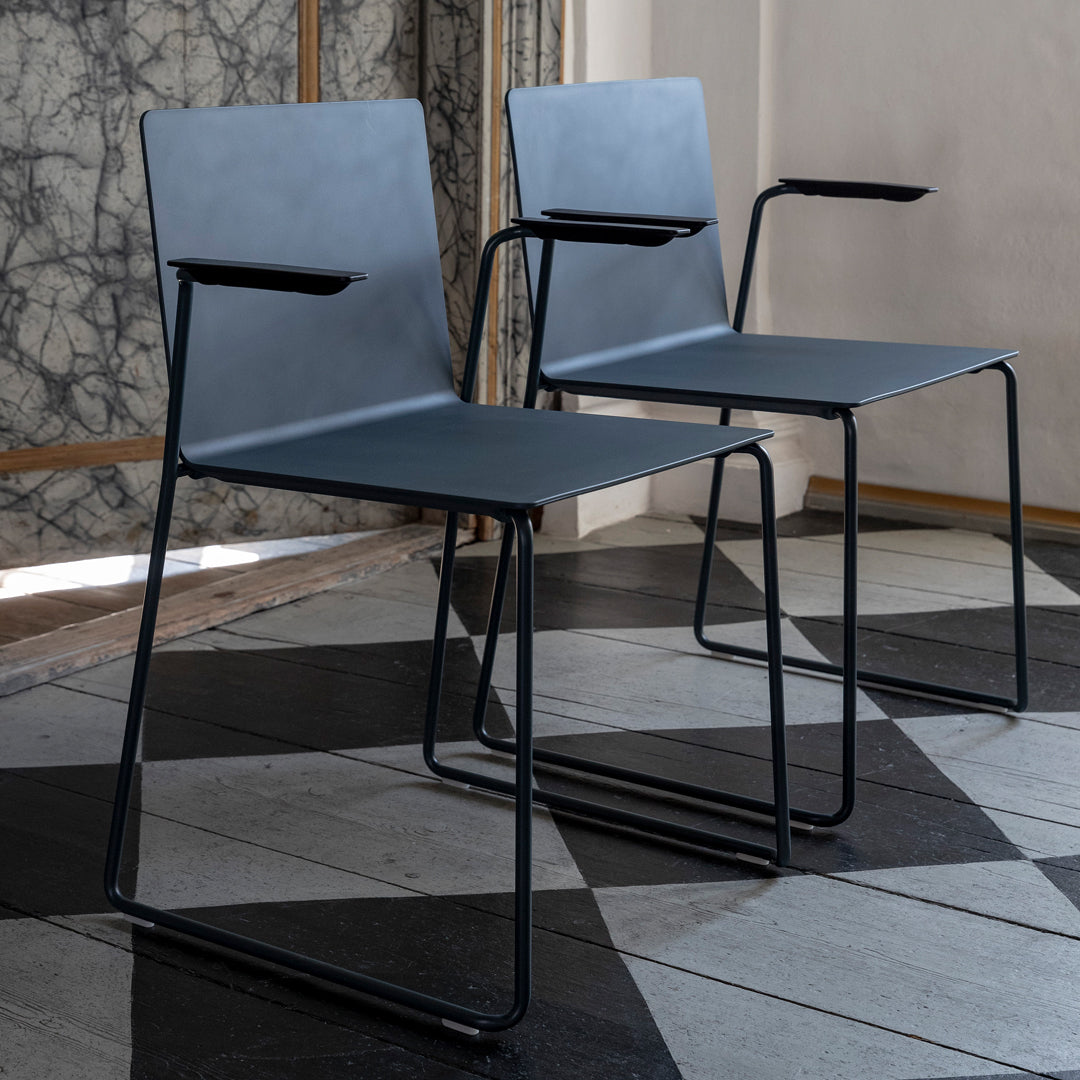 Two modern chairs with a sleek gray design and minimalist black frames, set against a geometric tiled floor.
