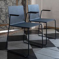 Two modern chairs with a sleek gray design and minimalist black frames, set against a geometric tiled floor.