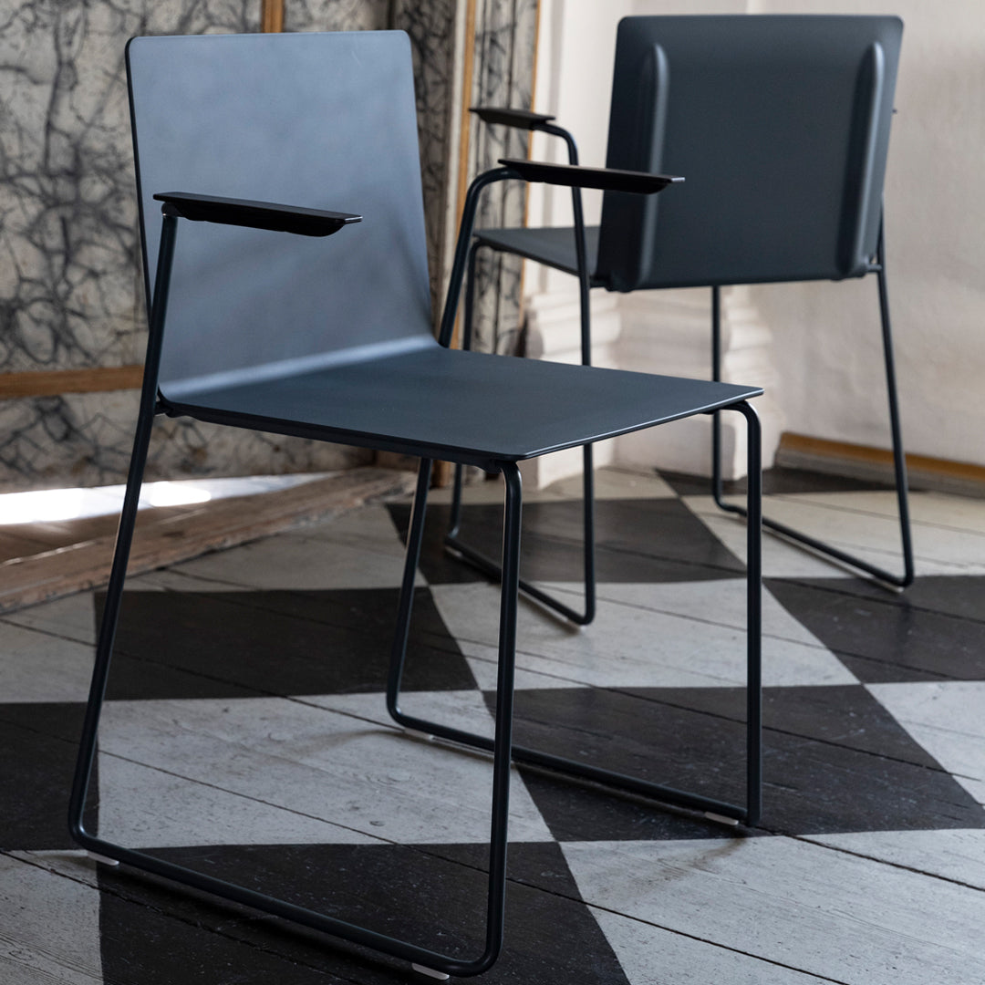 Modern gray metal chairs with sleek black legs, set against a geometric black and white patterned floor.