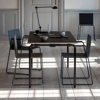 Black rectangular dining table with minimalist gray chairs, featuring sleek lines and a modern, neutral aesthetic.