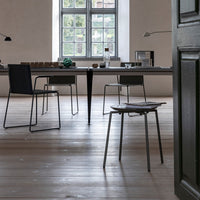 Modern dining room featuring sleek black chairs and a minimalist table, set against neutral walls and light wood flooring.