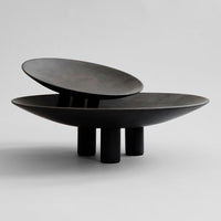 Black ceramic bowls with smooth, matte finish and unique layered design on a minimalist background.