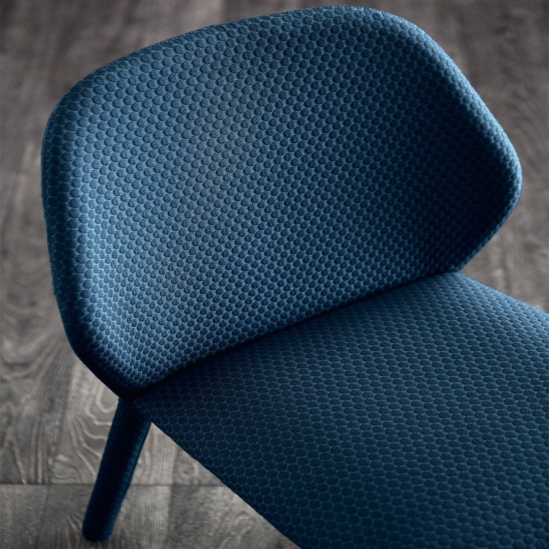 Textured dark blue chair with a woven pattern, featuring a smooth, curved backrest and sleek legs.