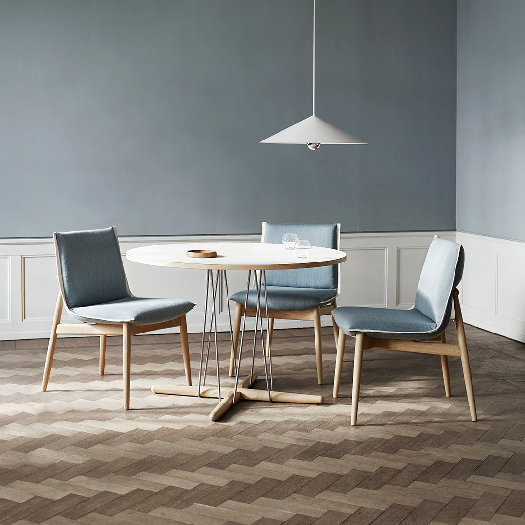Modern dining set featuring light blue chairs, a round white table, and a textured brown herringbone floor.