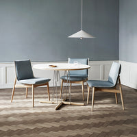 Modern dining set featuring light blue chairs, a round white table, and a textured brown herringbone floor.