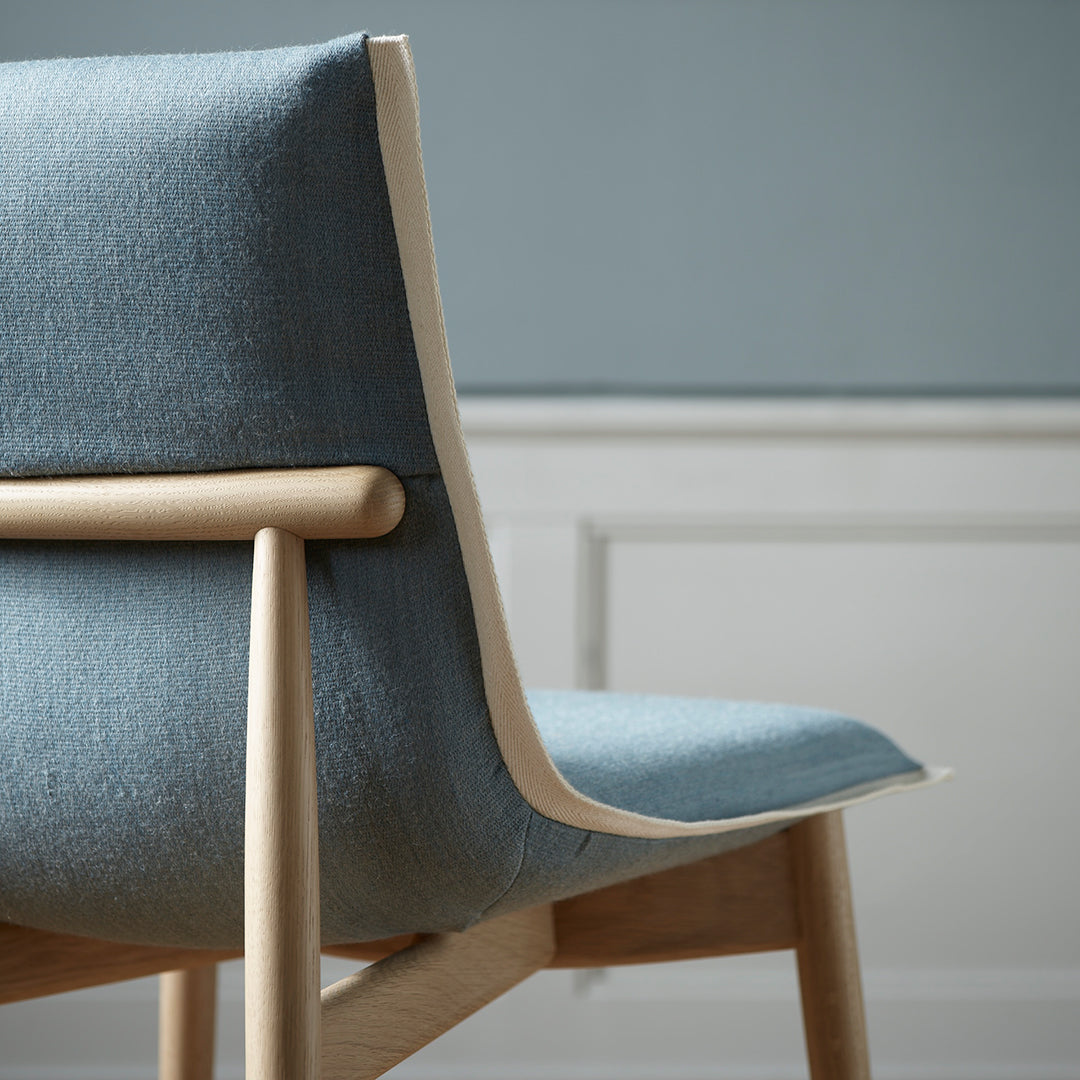 "Light blue upholstered chair with a smooth finish and natural wood accents, perfect for modern decor."