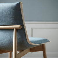 "Light blue upholstered chair with a smooth finish and natural wood accents, perfect for modern decor."