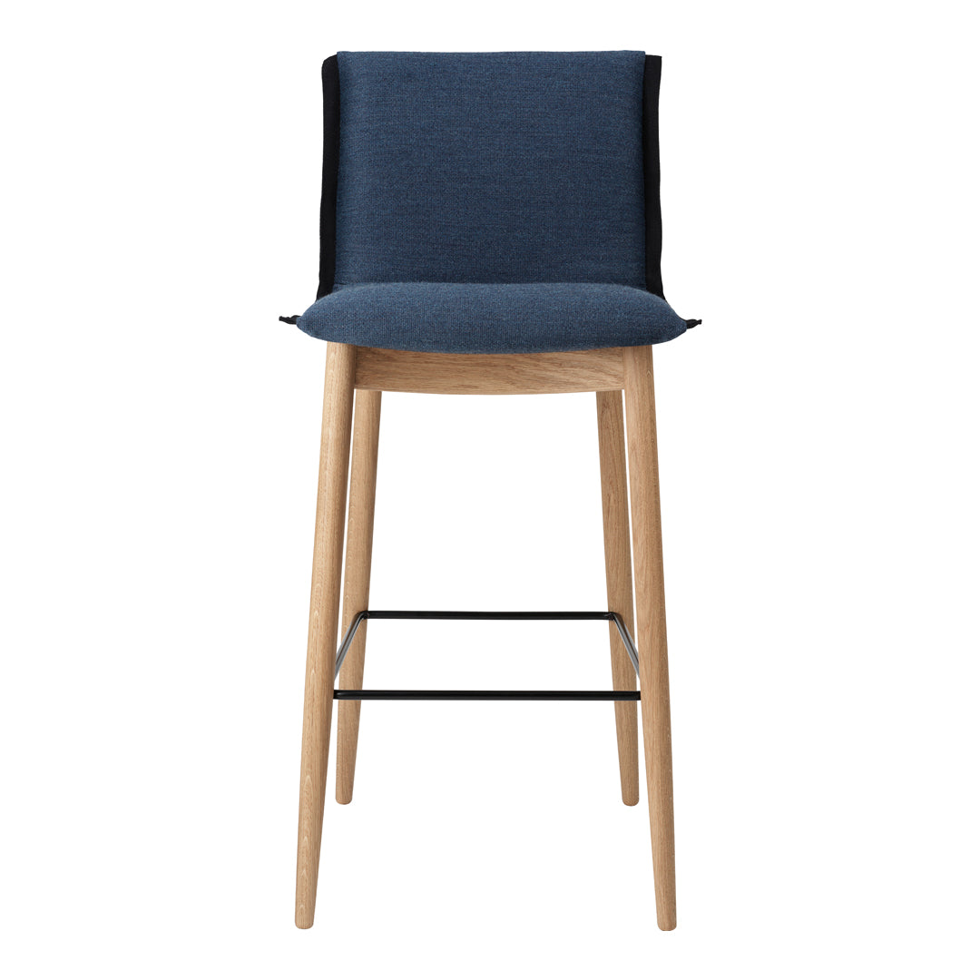 Navy blue upholstered bar stool with a light wood frame and black metal footrest. Modern, minimalistic design.