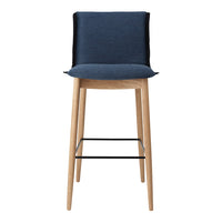 Navy blue upholstered bar stool with a light wood frame and black metal footrest. Modern, minimalistic design.