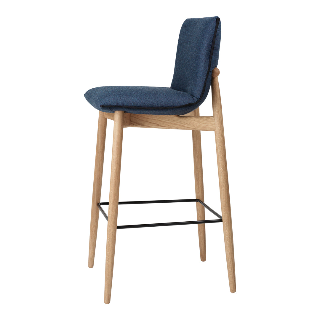 Navy blue upholstered bar stool with natural wood legs and a sleek black footrest, perfect for modern interiors.