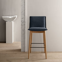 Modern dark blue upholstery on a wooden bar stool against a neutral background. Minimalist design and clean lines.