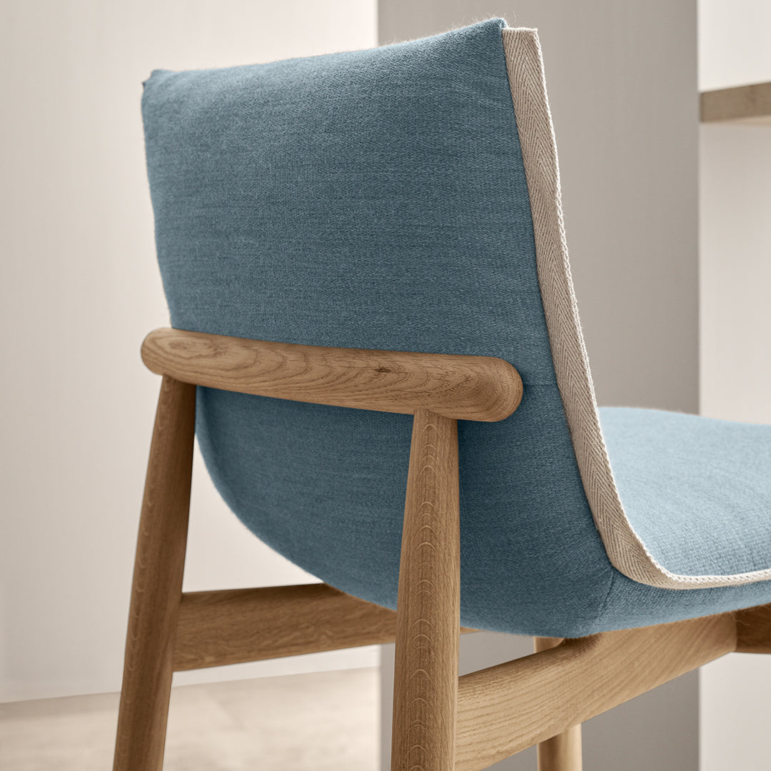 Blue lounge chair with a textured fabric and contrasting beige piping on the edge of the backrest.