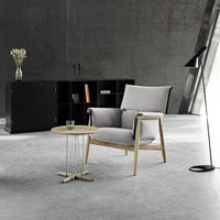 Light gray upholstered chair with natural wood legs, paired with a minimalistic wood table and sleek black accents.