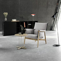 Gray upholstered armchair with light wood accents, paired with a round coffee table and minimalist decor.