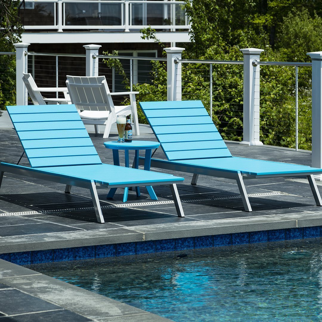 Two sleek, blue lounge chairs with slatted design beside a pool, complemented by a matching side table.