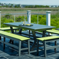 "Gray outdoor dining table with vibrant green benches, set against a scenic background."