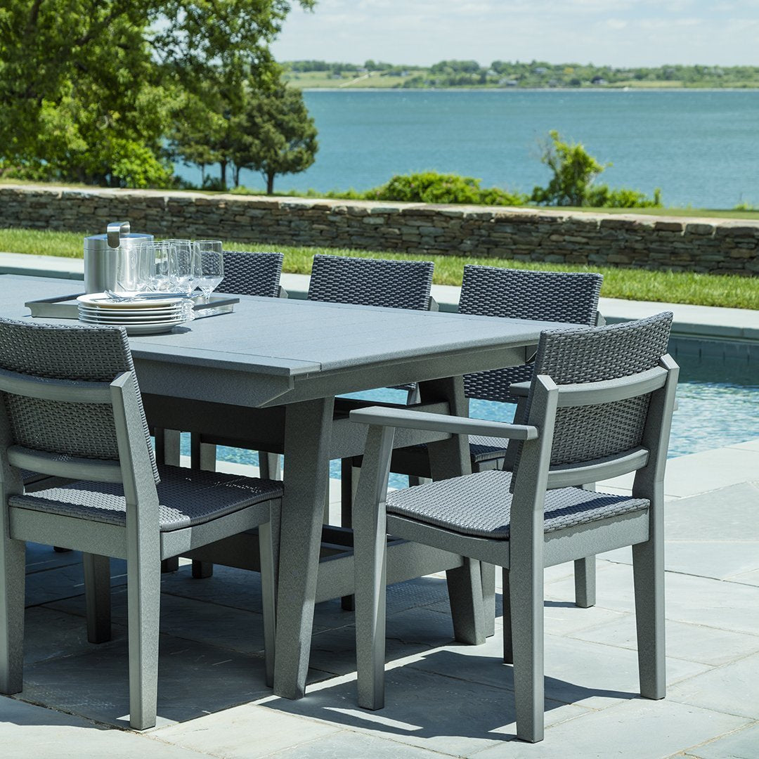 Gray outdoor dining table and chairs set against a serene lake view, featuring sleek, modern design and textured patterns.