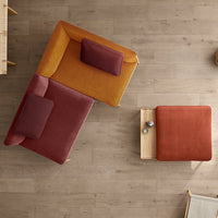 Modern armchairs in mustard yellow and deep burgundy upholstery with coordinating pillows, set on a light wooden floor.