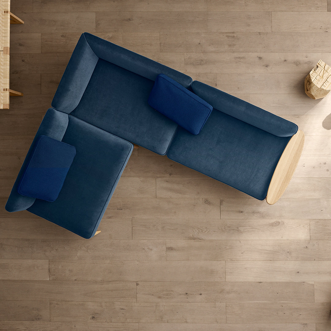 "Modern L-shaped sofa in rich navy blue with plush cushions, set against a light wooden floor."
