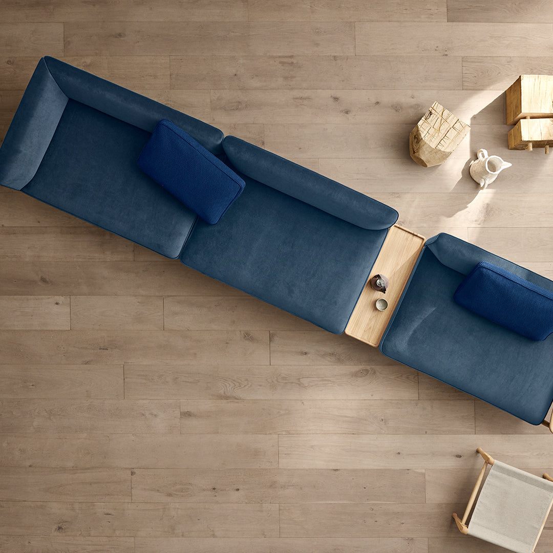 "Modern blue sectional sofa with deep cushions and light wood accents, featuring a sleek, minimalist design."