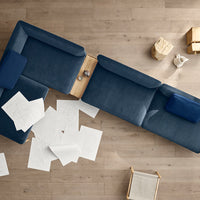 Navy blue sectional sofa with smooth fabric and clean lines, complemented by light wood accents and neutral-colored decor.