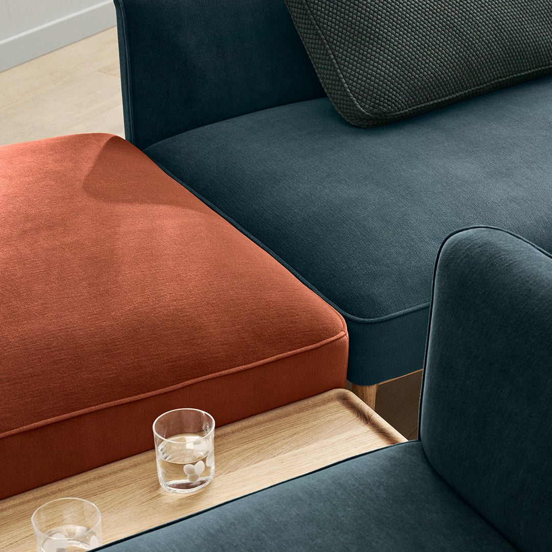 Teal and burnt orange sofa with textured cushions and smooth fabric, perfect for a modern living space.