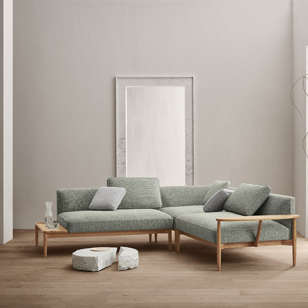 Light green sofa with a textured finish, paired with light wood accents and soft, patterned throw pillows.